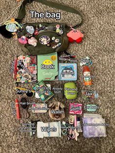 the contents of a purse are laid out on the floor, including books and other items