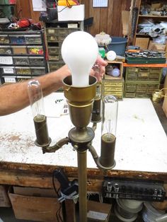 an old fashioned lamp is being worked on by a man in a workshop with other tools