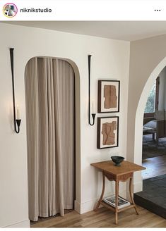 a living room with an arched doorway and pictures on the wall, along with a small table