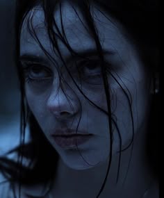 a close up of a person with wet hair and eyes looking at the camera while holding a cell phone