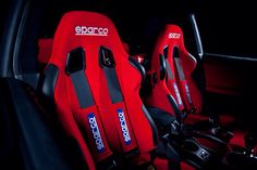 two red seats in the back of a car, one with black and white logos