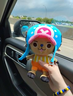 a person holding a stuffed animal in their hand while sitting in the driver's seat of a car