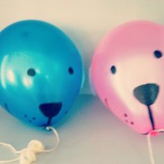 two blue and pink balloons with faces on them sitting next to each other in the shape of a bear