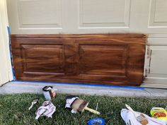 the front door is being painted brown and there are some tools on the grass outside