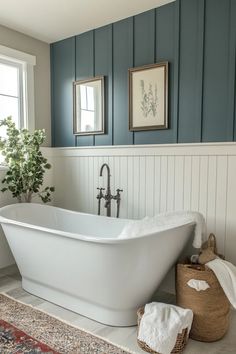 a white bath tub sitting in a bathroom next to a rug and two pictures on the wall