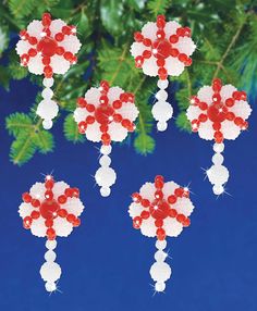 four red and white beads hanging from a christmas ornament on a tree branch