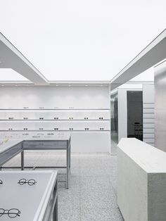 an empty store with glasses on display in the window and behind them is a bench