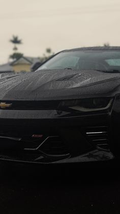 a black chevrolet camaro parked in a parking lot next to other cars on a cloudy day