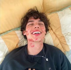 a young man laying on top of a bed with his tongue hanging out to the side