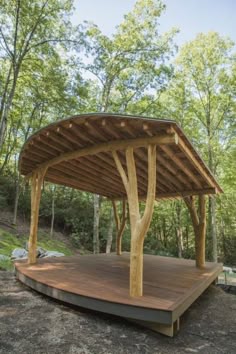 a wooden gazebo in the middle of a wooded area