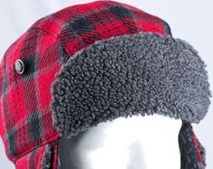 a white mannequin head wearing a red and black plaid hat with ear flaps