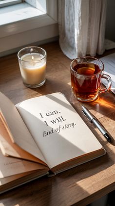 an open book sitting on top of a wooden table next to a cup of coffee