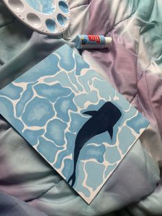 a dolphin painted on a piece of paper next to some paintbrushes and an acrylic palette