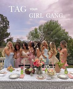 a group of women standing around a table with plates on it and flowers in vases