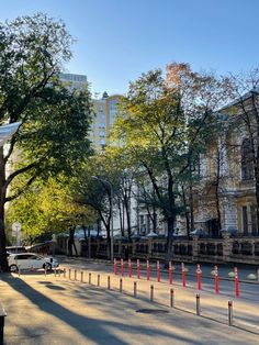 an empty street lined with trees and orange cones in front of tall buildings on the other side