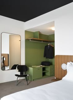 a bedroom with a bed, mirror and closet in it's corner next to a chair