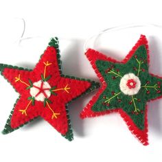 two red and green christmas stars hanging on a white wall next to each other in the shape of an ornament