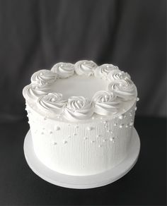 a white cake with frosting roses on top is sitting on a black tablecloth