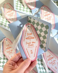 someone holding an origami dog tag in front of some tags on the wall