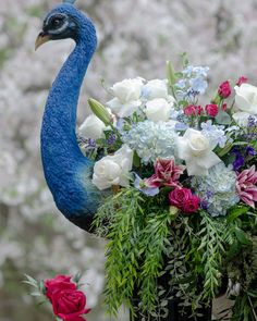 a blue bird sitting on top of a vase filled with flowers