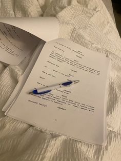 an open book with writing on it and a blue pen laying next to the page