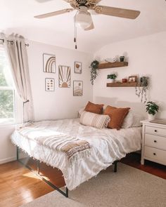 a bedroom with a bed, dresser and ceiling fan in the corner next to a window