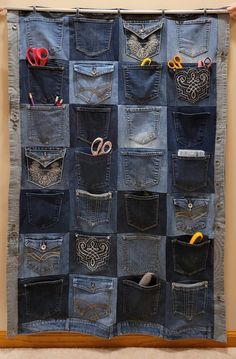 an old pair of jeans hanging on a wall with scissors and other items in it