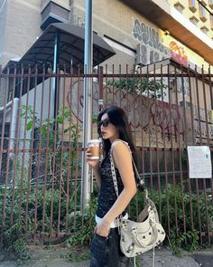 a woman walking down the street with a coffee cup in her hand and a purse on her shoulder