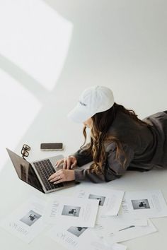 a woman is laying on the floor with her laptop in front of her and papers all around her