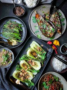 an assortment of food on plates with chopsticks and spoons next to them