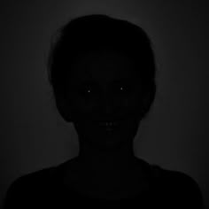 a woman is shown in the dark with her face glowing from behind an electronic device