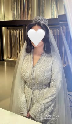 a woman in a wedding dress with a white heart on her forehead and veil over her head