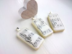 three pieces of jewelry with musical notes on them next to a heart shaped piece of wood