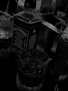 a bottle of jack daniels sitting on top of a table next to two glasses filled with ice