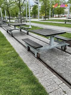 several benches are lined up on the side of a path near grass and street lights
