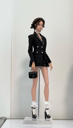 a barbie doll dressed in a black suit and high heeled shoes holding a purse