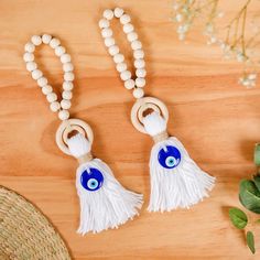 two wooden beads with blue eyes and white tassels