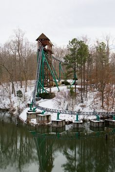 a roller coaster in the snow next to a body of water with trees around it