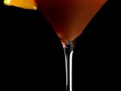 a close up of a martini with an orange slice on the rim