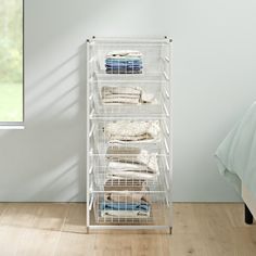 a white rack with clothes on it next to a bed