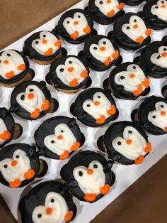 there are many cupcakes decorated like penguins with orange and white frosting on them