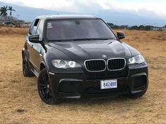 a black car parked on top of a dry grass field
