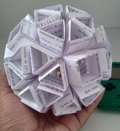 a hand holding a paper origami ball with words written on it in different languages
