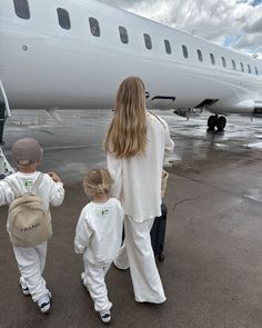 a woman and two children walking towards an airplane