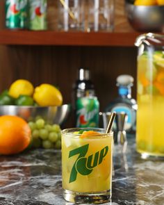 a glass filled with liquid sitting on top of a counter next to oranges and lemons