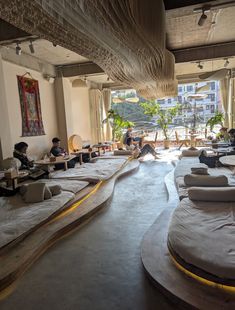 people are sitting on bean bags in the middle of a room with large windows and floor to ceiling curtains