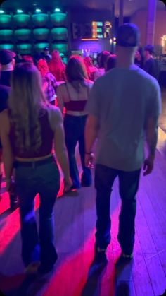 people are dancing on the dance floor in a club or bar with bright lights and wooden floors