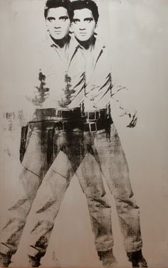 two men standing next to each other in front of a white wall