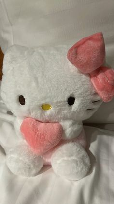 a hello kitty stuffed animal sitting on top of a white bed sheet with pink ears
