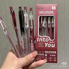 a person holding some pens in front of a box with the words into you written on it
